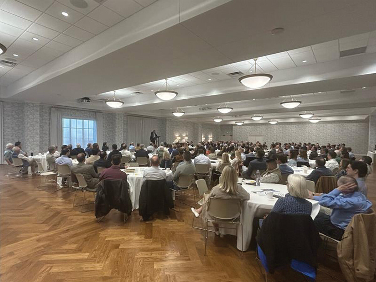 Large church gathering seated at round tables listening to speaker.